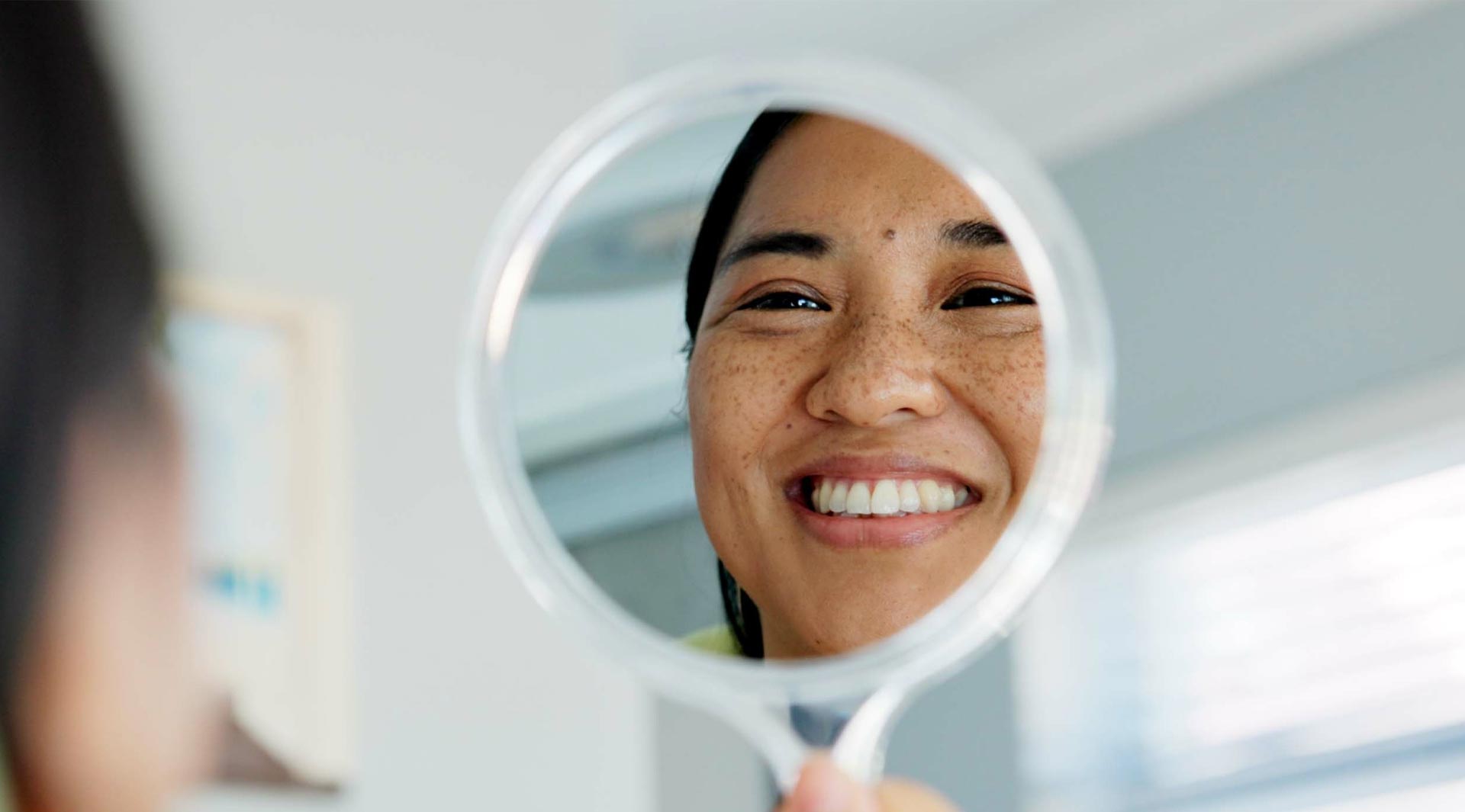 A person looking at their reflection in a mirror with a joyful expression.