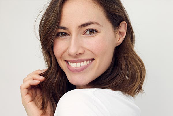 A woman with short hair smiles at the camera, looking directly ahead, against a light background.
