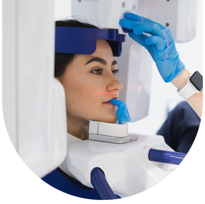 A woman wearing blue gloves is seated inside an advanced medical imaging machine, likely an MRI or CT scan device.