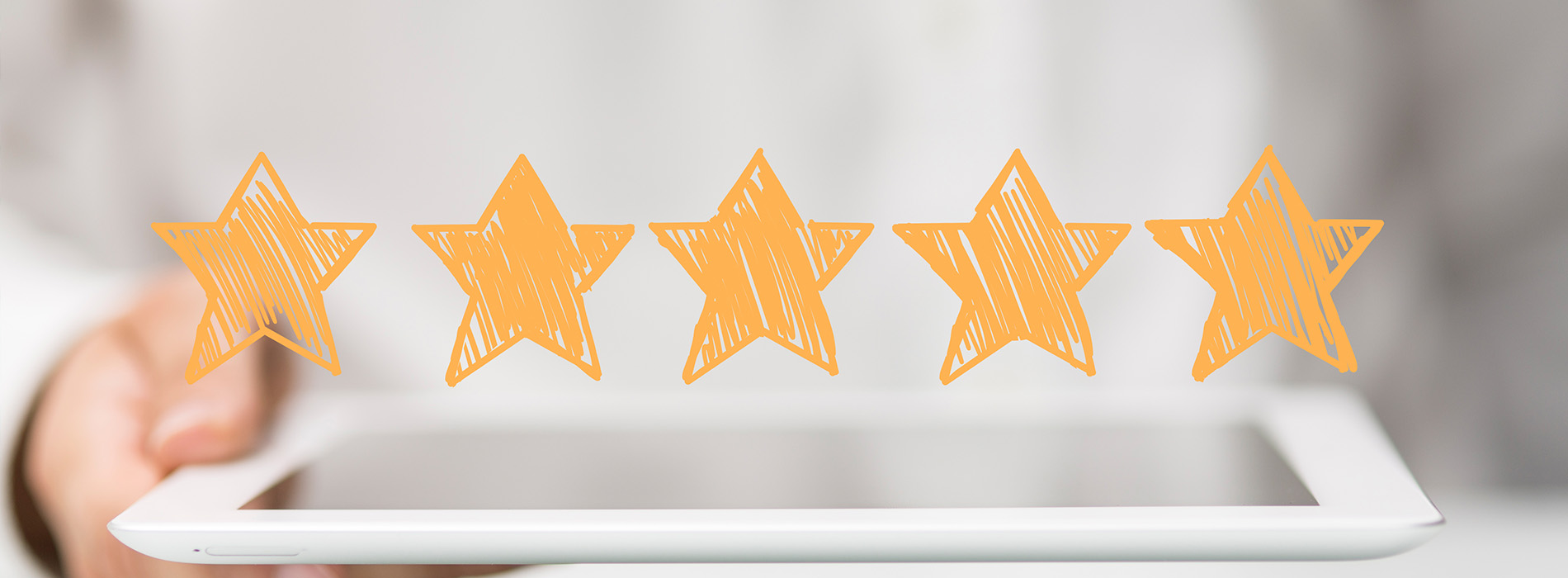 The image shows a person holding a tablet displaying five orange stars against a blurred background.