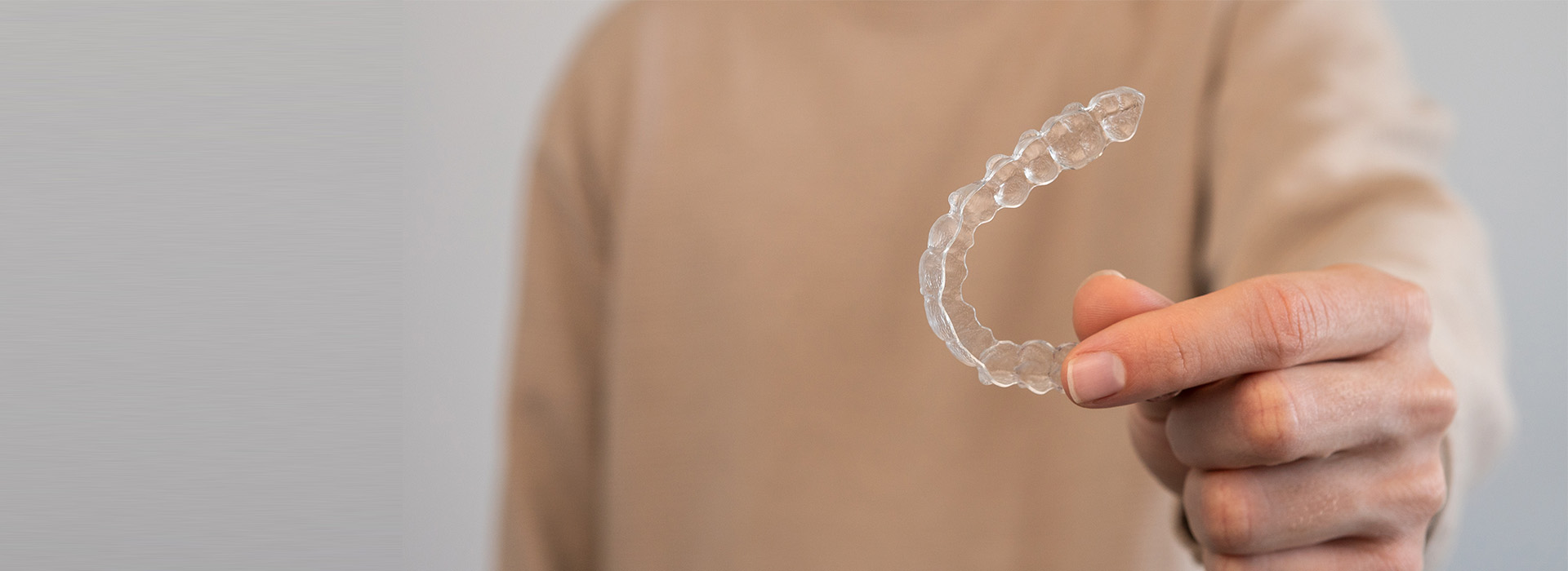 The image shows a person s hand holding a clear, circular object against their face, with the background blurred and indistinct.