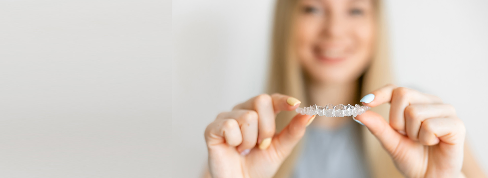 The image features a person holding up a small object with their hand, against a plain background.
