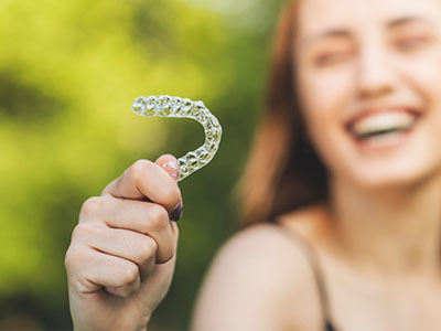The image shows a person holding up a toothbrush with a smile on their face, conveying a positive and oral hygiene theme.