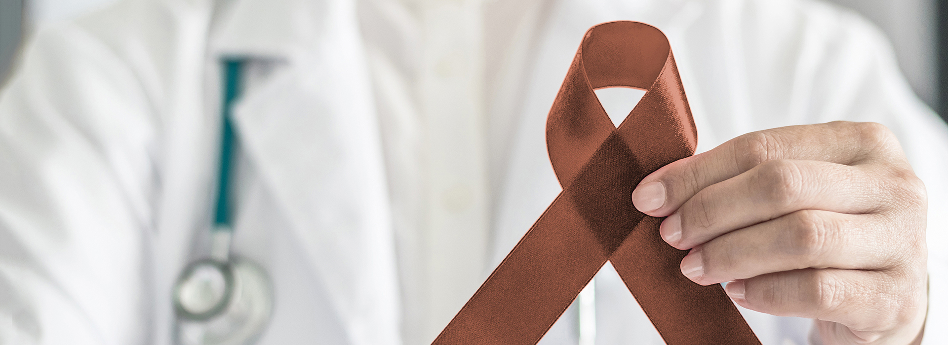 The image shows a medical professional holding up an AIDS awareness ribbon.