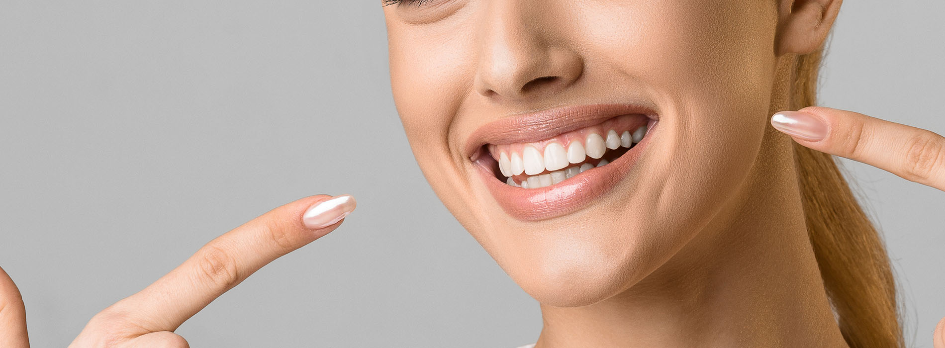 A smiling woman holding up two fingers with her left hand against a white background.