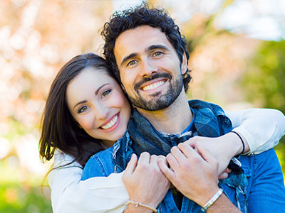 A man and woman embracing each other outdoors.