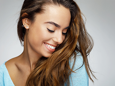 The image features a woman with long hair smiling at the camera, showcasing her profile against a white background.