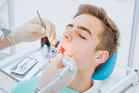 A dentist performing oral surgery on a patient while wearing protective gloves.