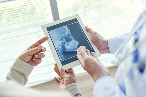 Two people viewing a tablet displaying an X-ray, with one person holding the tablet and another pointing at it.