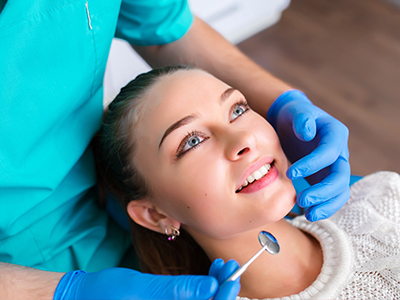 A dental professional performing a procedure on a patient's teeth with a smile.